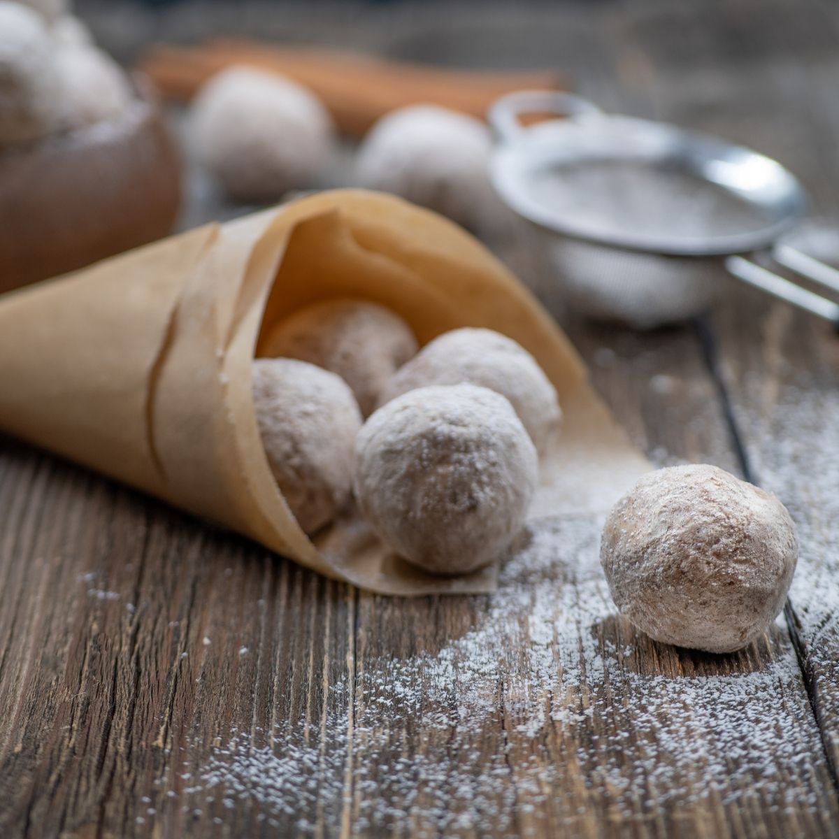 Air fryer donut holes with powdered sugar on a wooden table wrapped in brown parchment paper