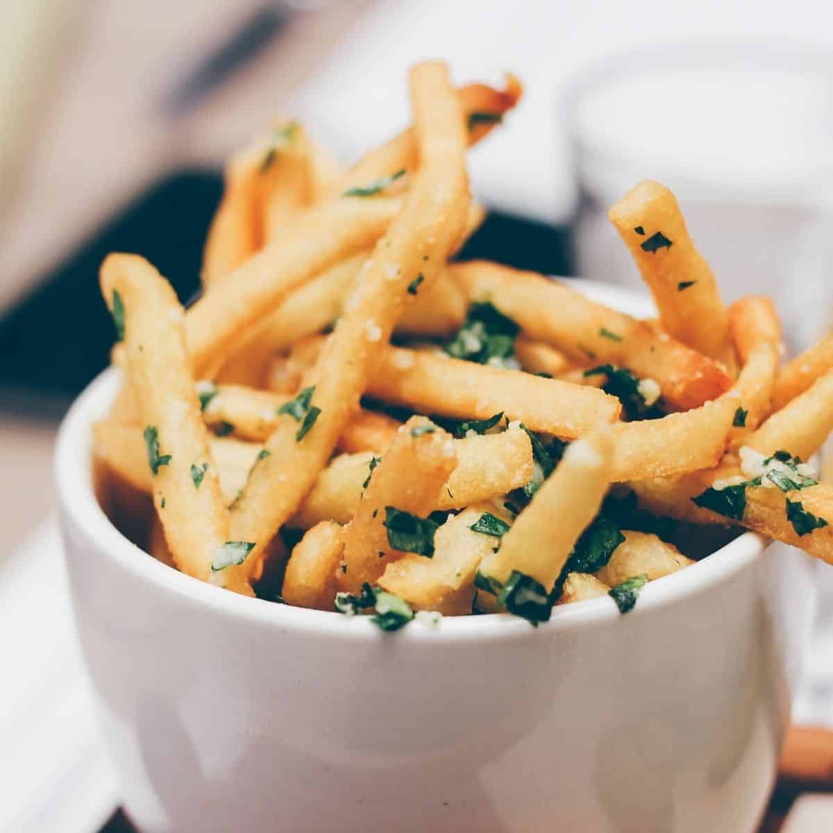 Air Fryer shoestring fries in a white bowl with chives