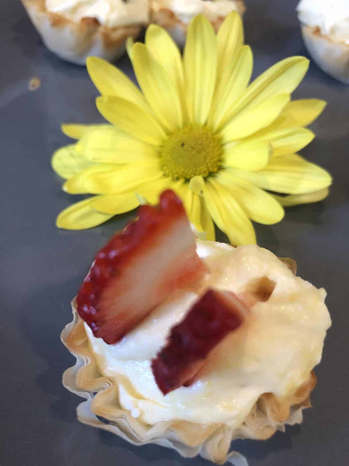 Lemon Zesty tartlet Topped with Sliced Strawberry and a yellow flower