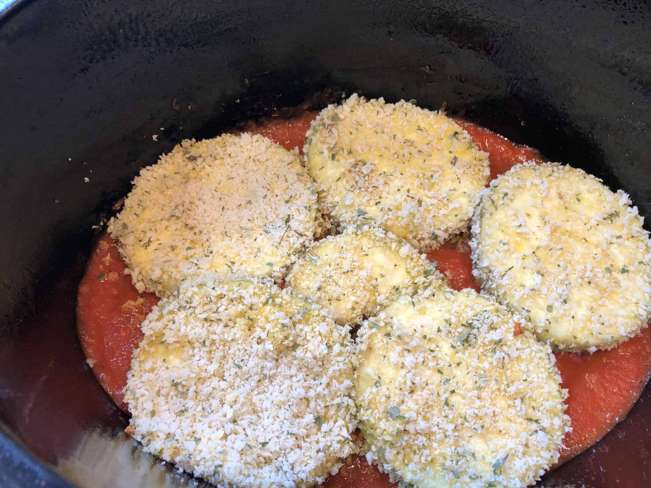 Breaded Eggplant slices layered in a crockpot with marinara sauce