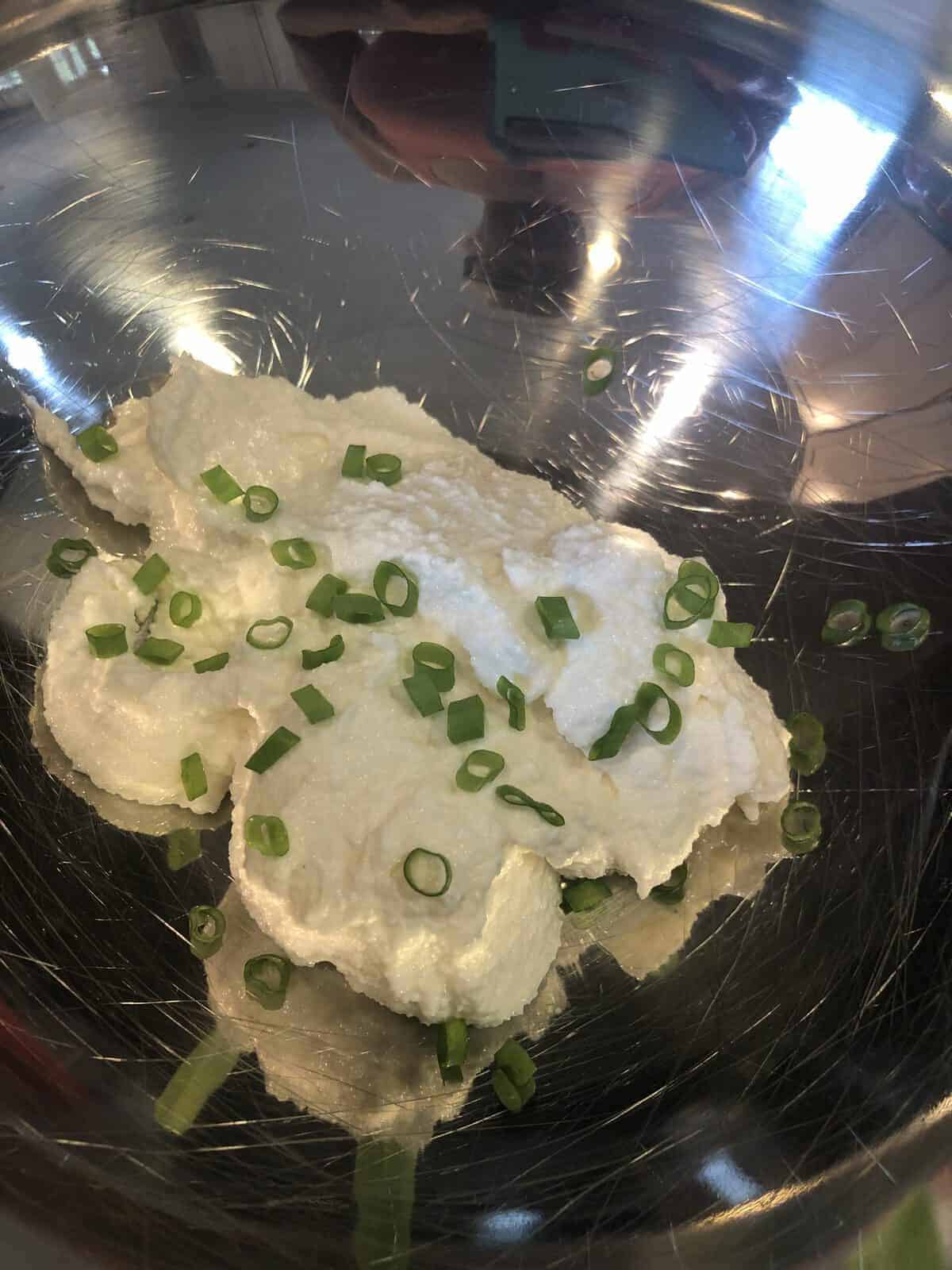 Herbed Ricotta and scallions in a stainless steel bowl
