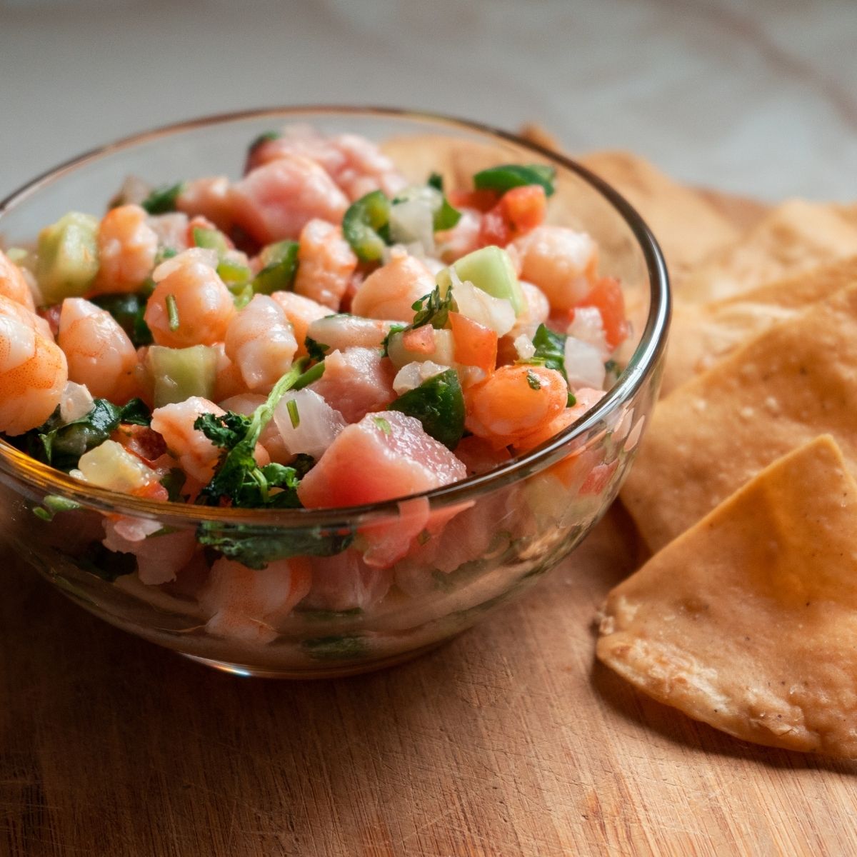 Shrimp ceviche in a glass bowl with 4 tostada chips on the side