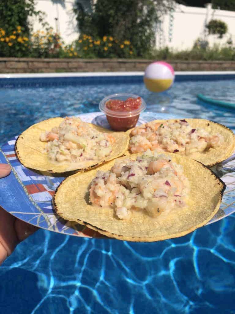 3 shrimp salad tortillas on a blue plate with salsa by the pool