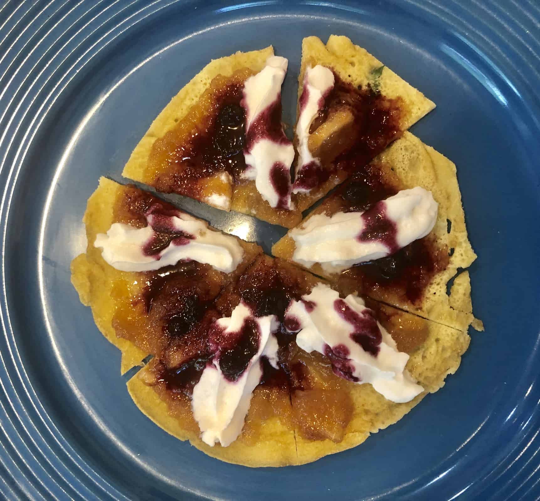 A Chickpea Crepe Pizza with whipped cream and berry jam on a blue plate