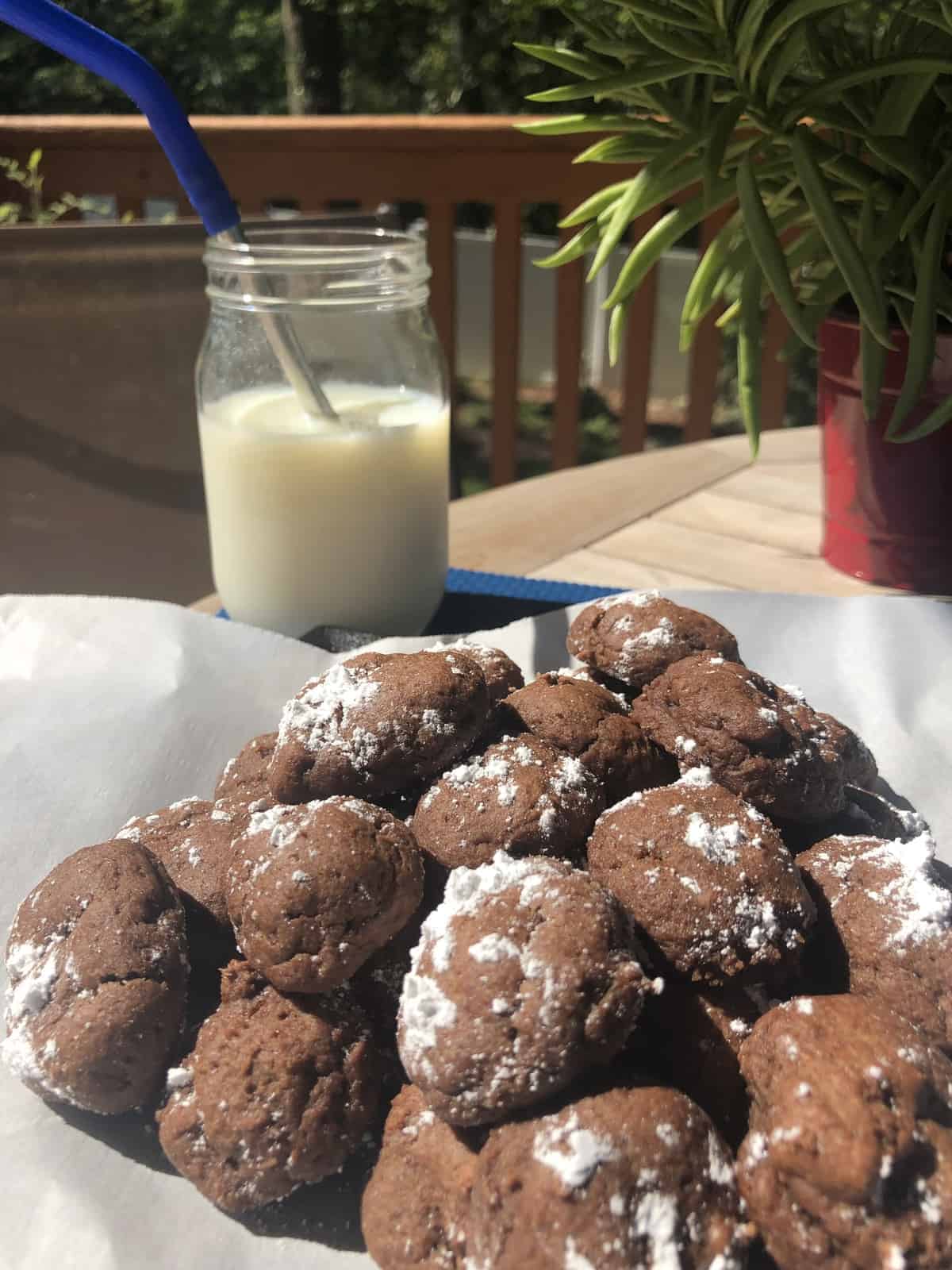 a pile of chocolate bon bons on parchment paper with a glass of milk