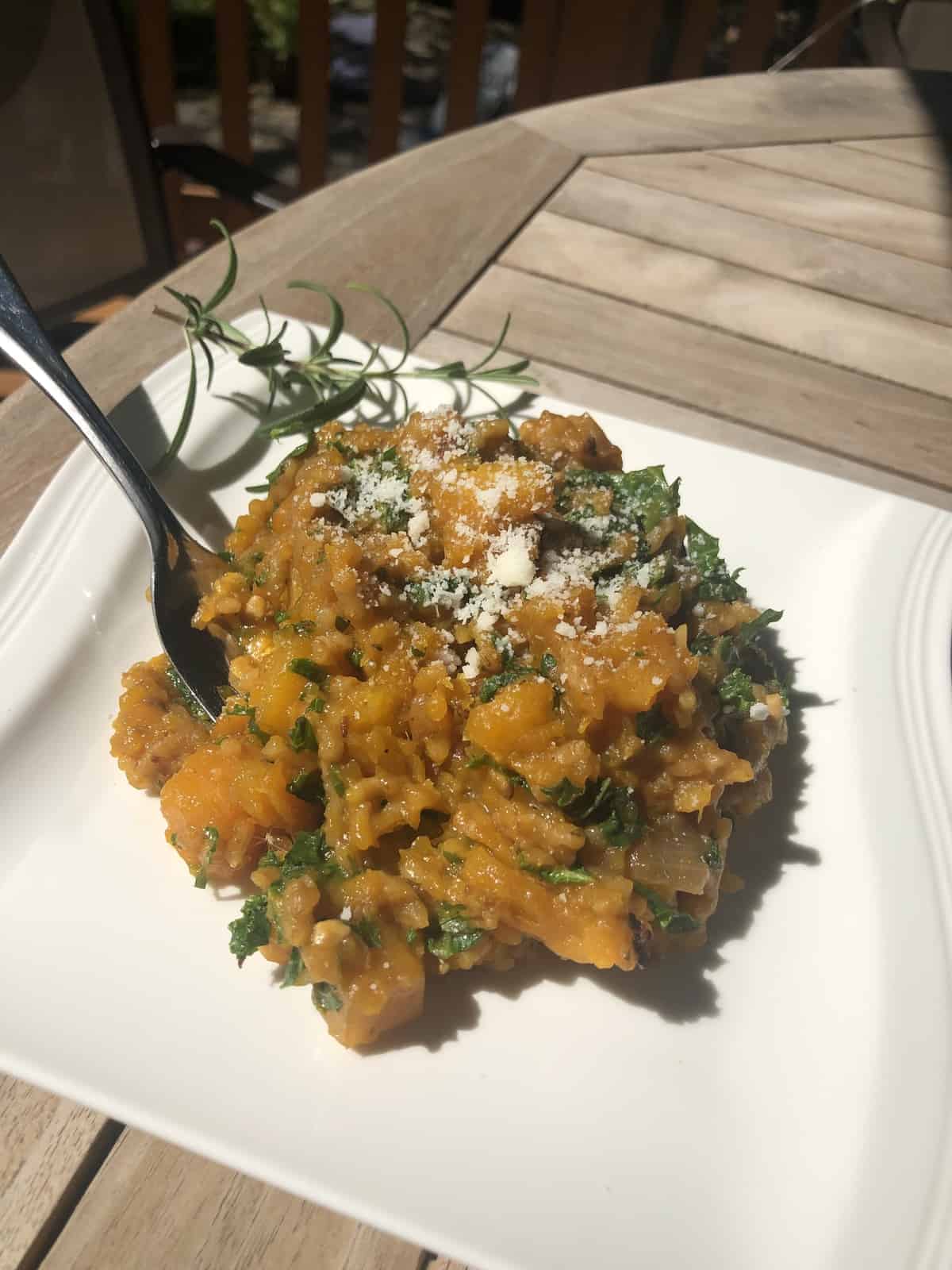 a spoonful of risotto over a plate of risotto on a wooden table