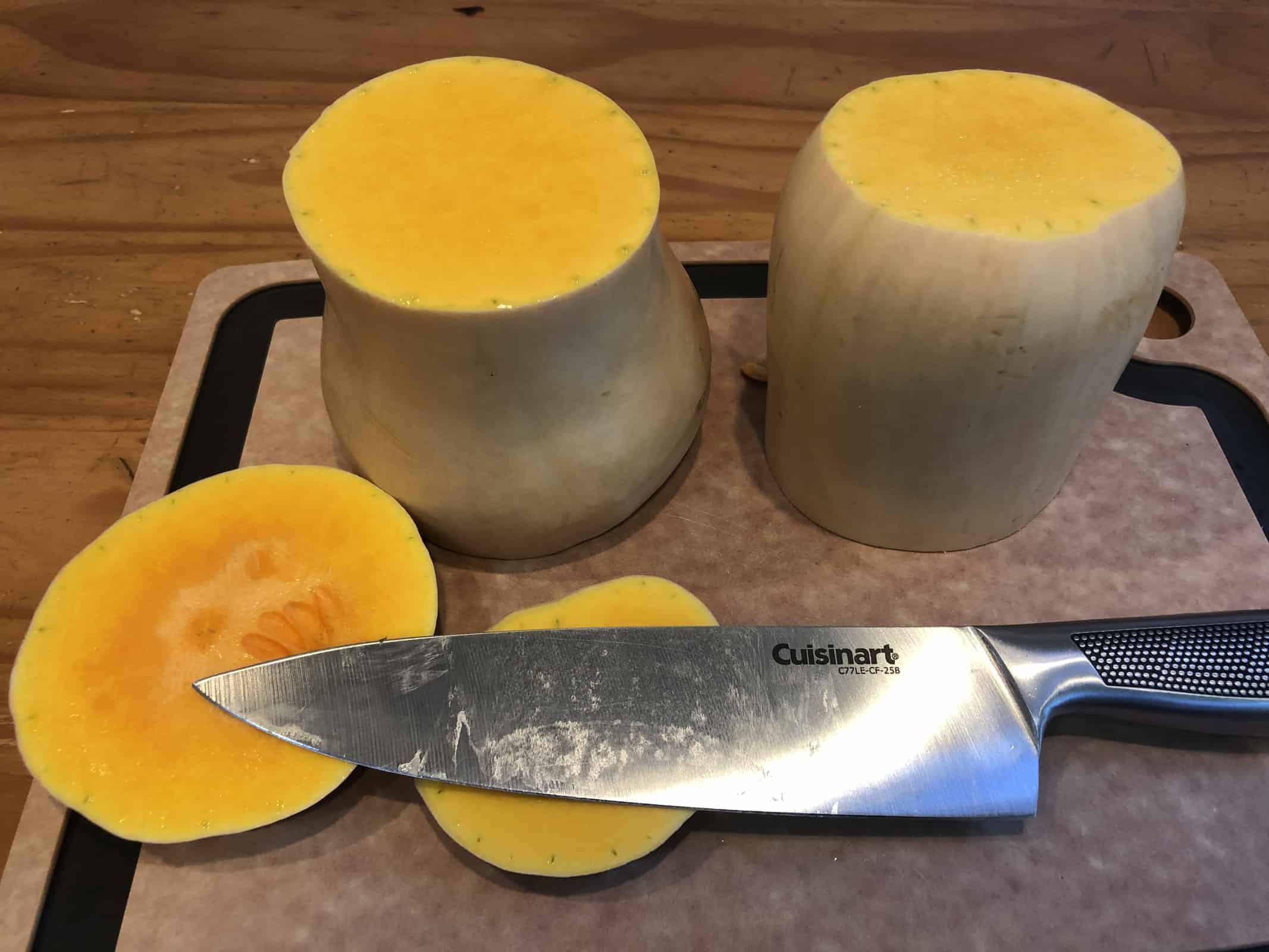 Chopping a butternut squash on a cutting board with a stainless steel knife