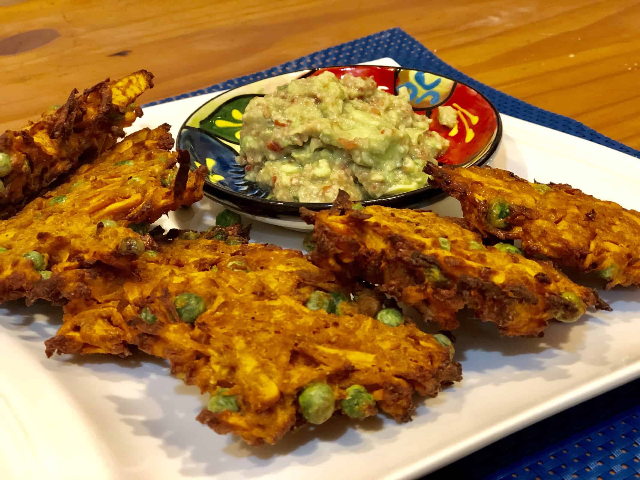 Five Sweet Potato Fritters on a white plate with guacamole dip