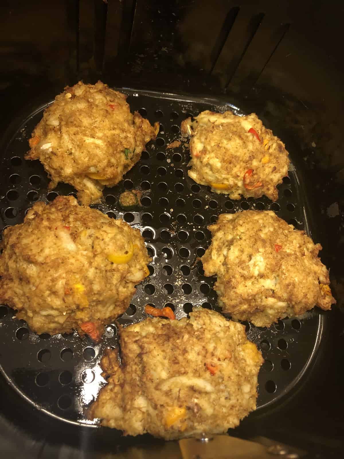 Five Freshly Air Fried Crab Cakes in the air fryer basket