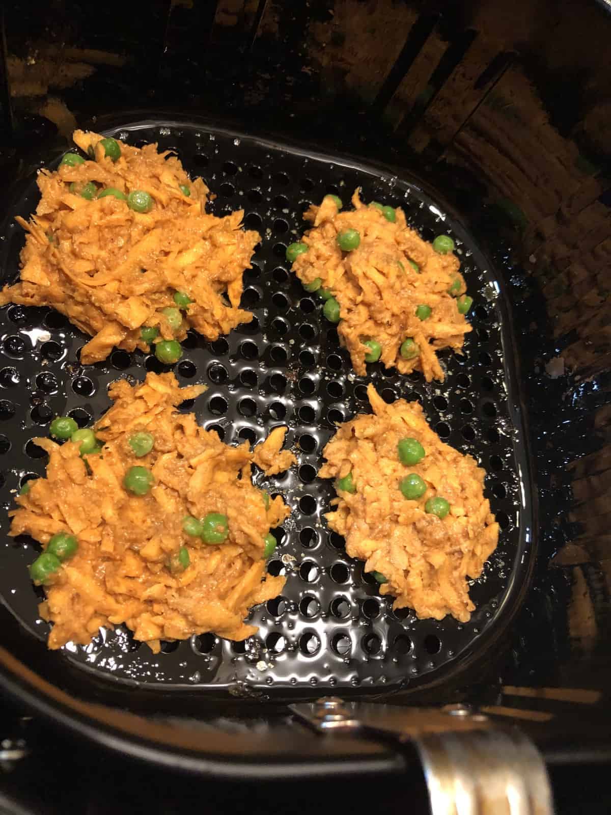 4 sweet potato fritters cooking in the air fryer basket