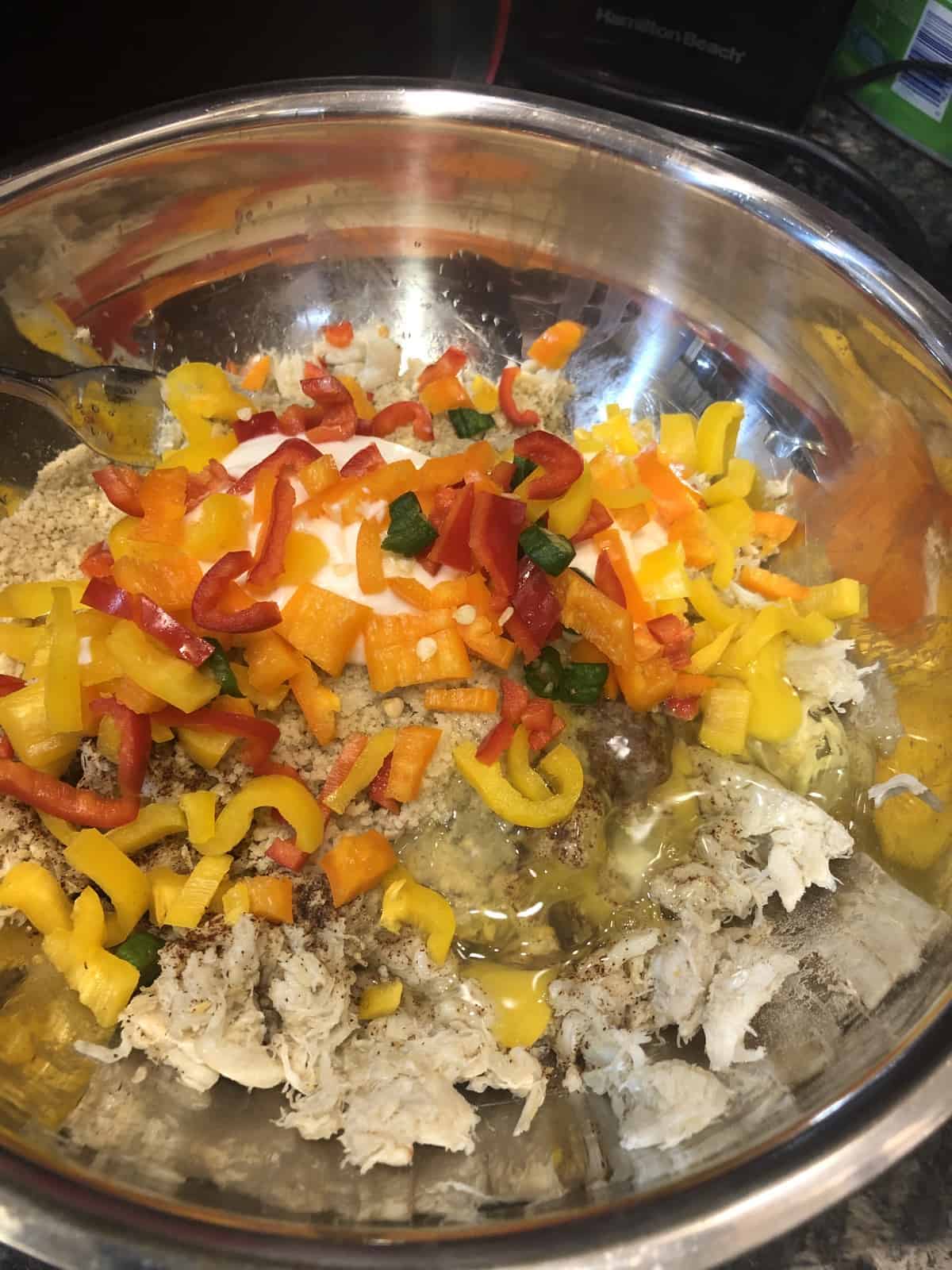 Jumbo lump crabmeat in a stainless steel bowl with seasoning