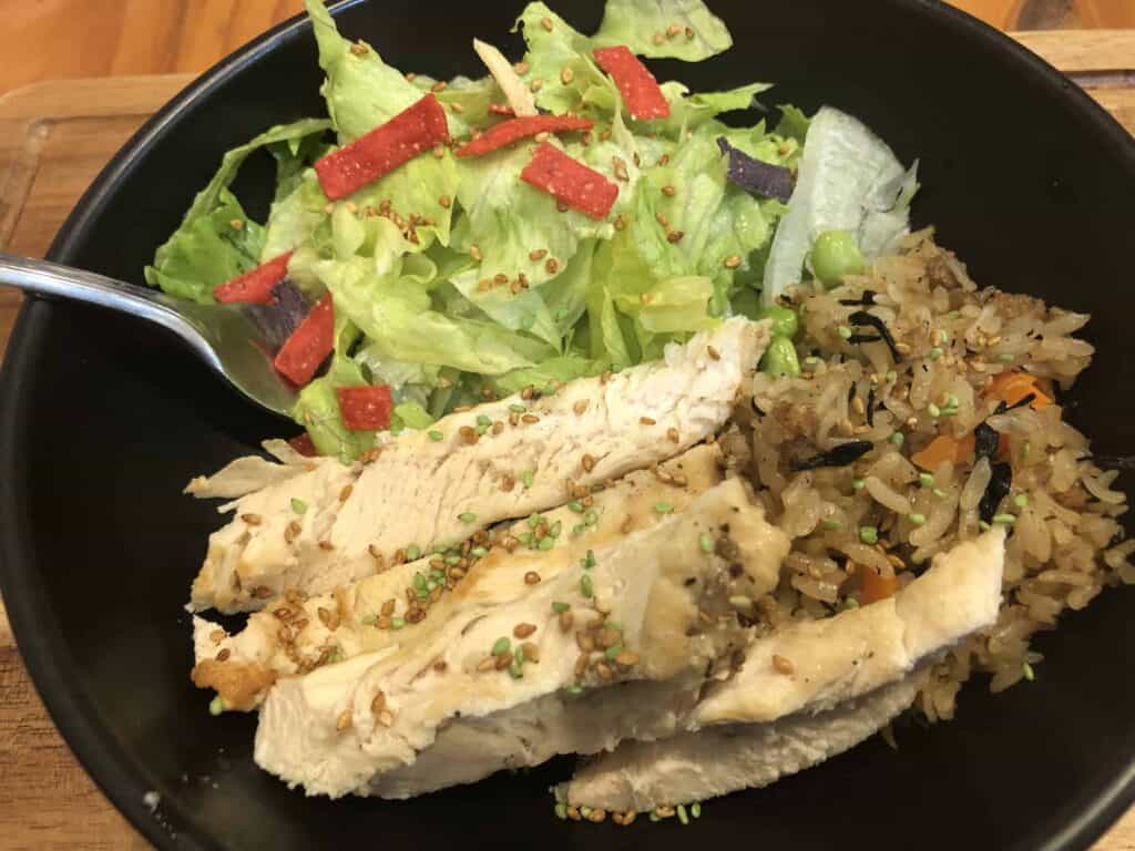 Mrs. Dash Instant Pot chicken in a black bowl with rice and salad