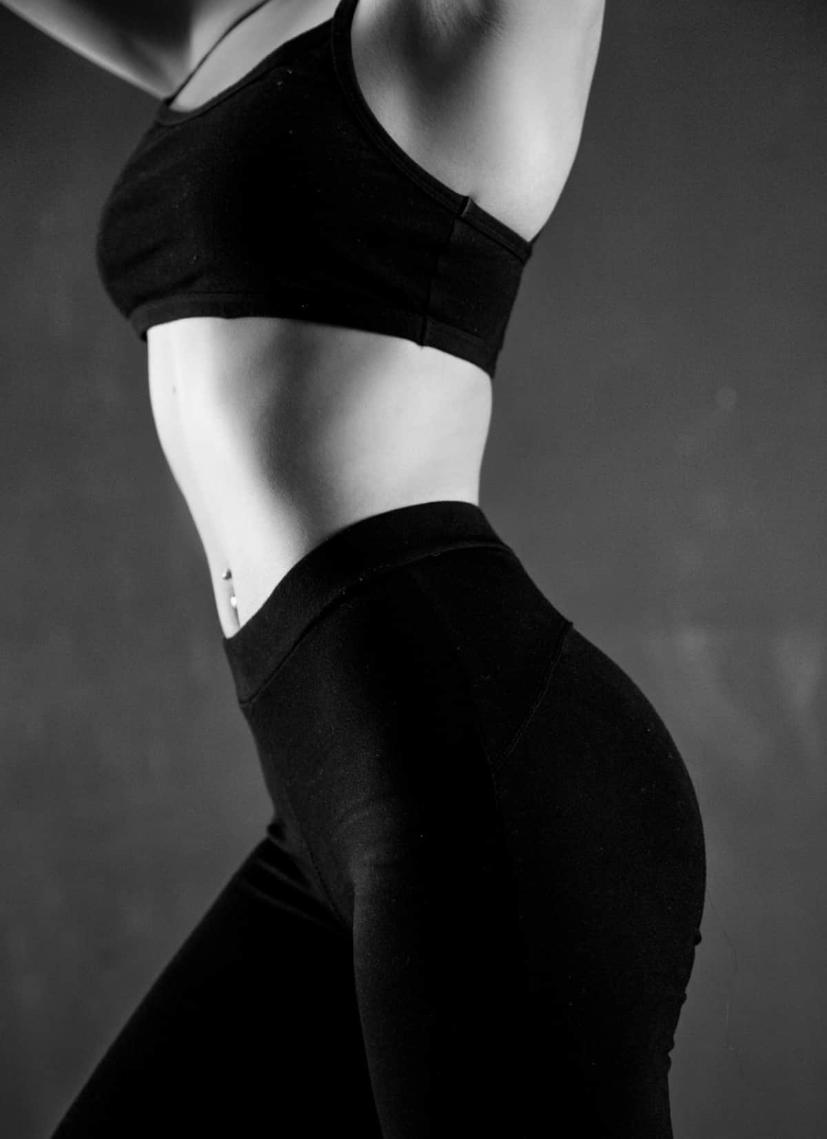 a healthy and fit female body in black leggings and a black crop top