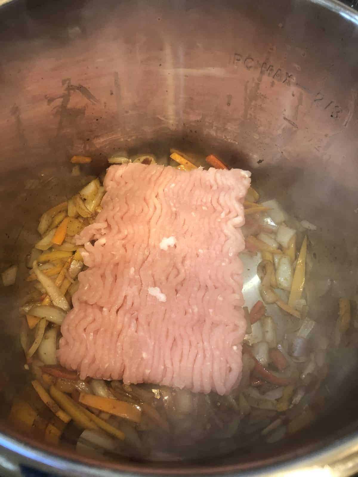 Sauteeing Chop meat in the Instant Pot with diced onions and peppers
