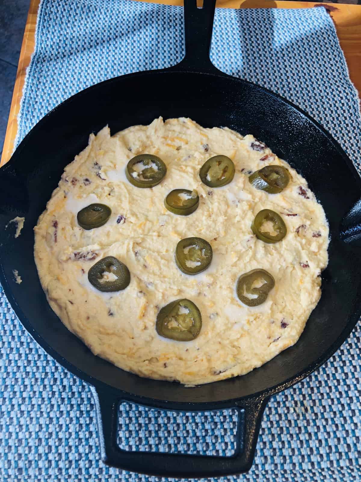 Keto Cornbread batter in the cast iron skillet on a blue placemat