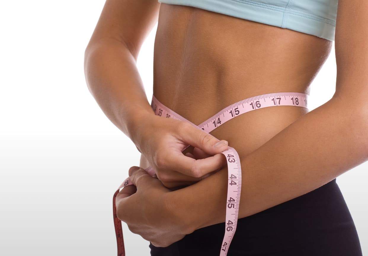 Female measuring her waist with a tape measure