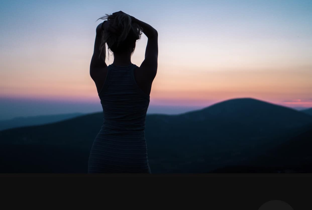 Healthy female meditating on a mountainside