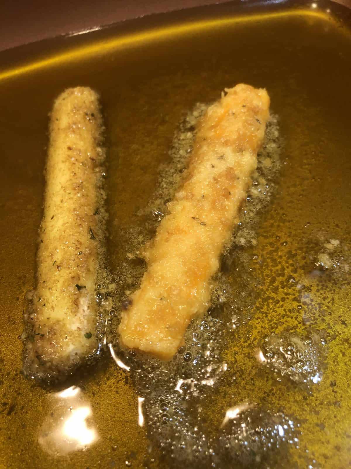 Two Low Carb Mozzarella Sticks frying in a copper pan