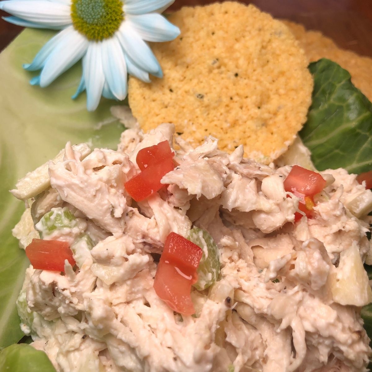 WW Ranch chicken salad with diced tomatoes on a cabbage leaf with parmesan crisp chip and a white daisy