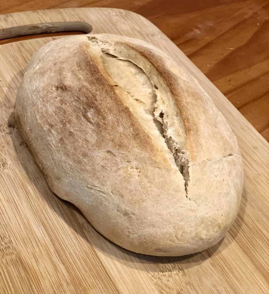 A loaf of homemade Italian bread on a wooden cutting board