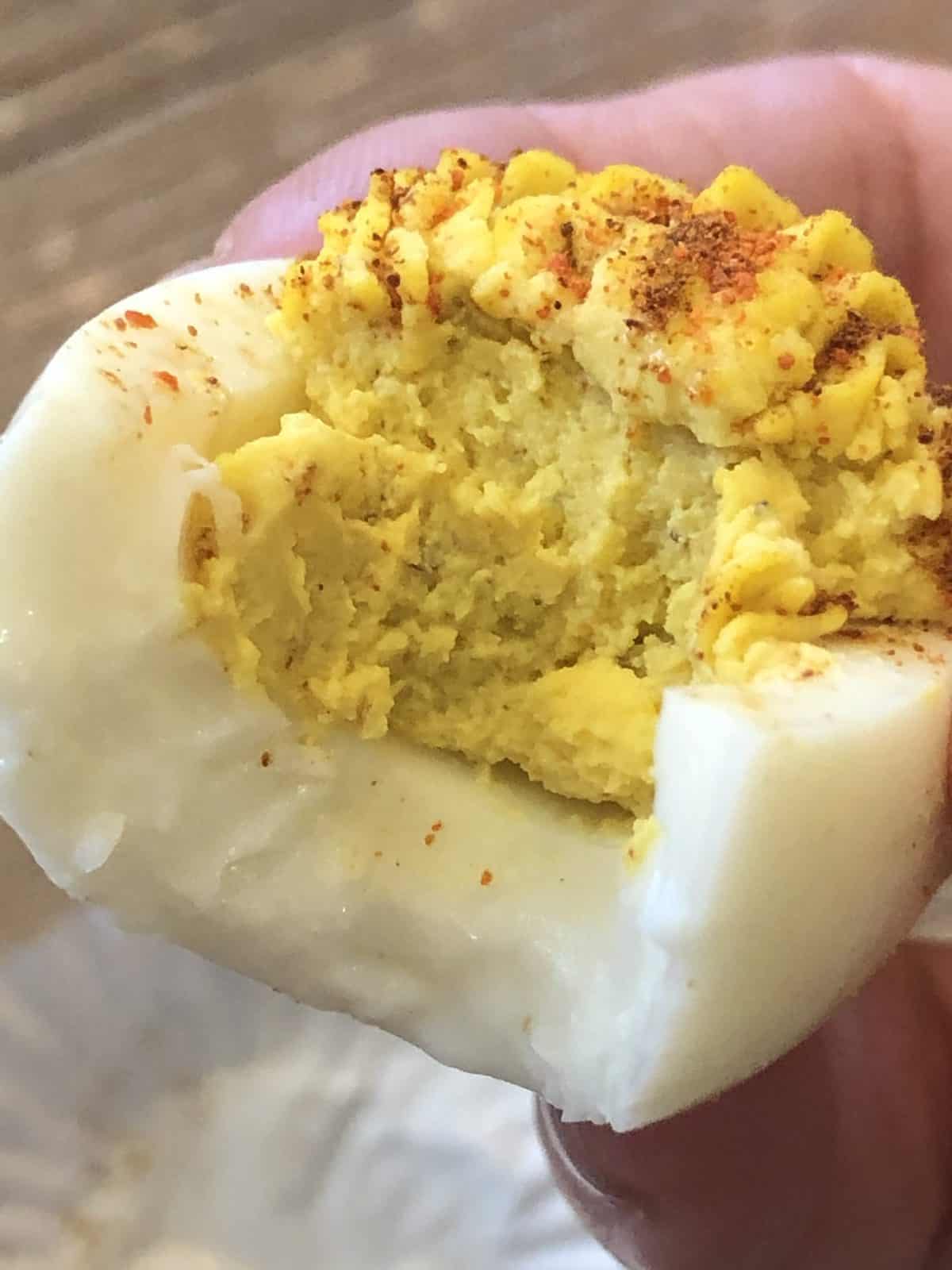 A hand holding a  bite of a WW deviled egg