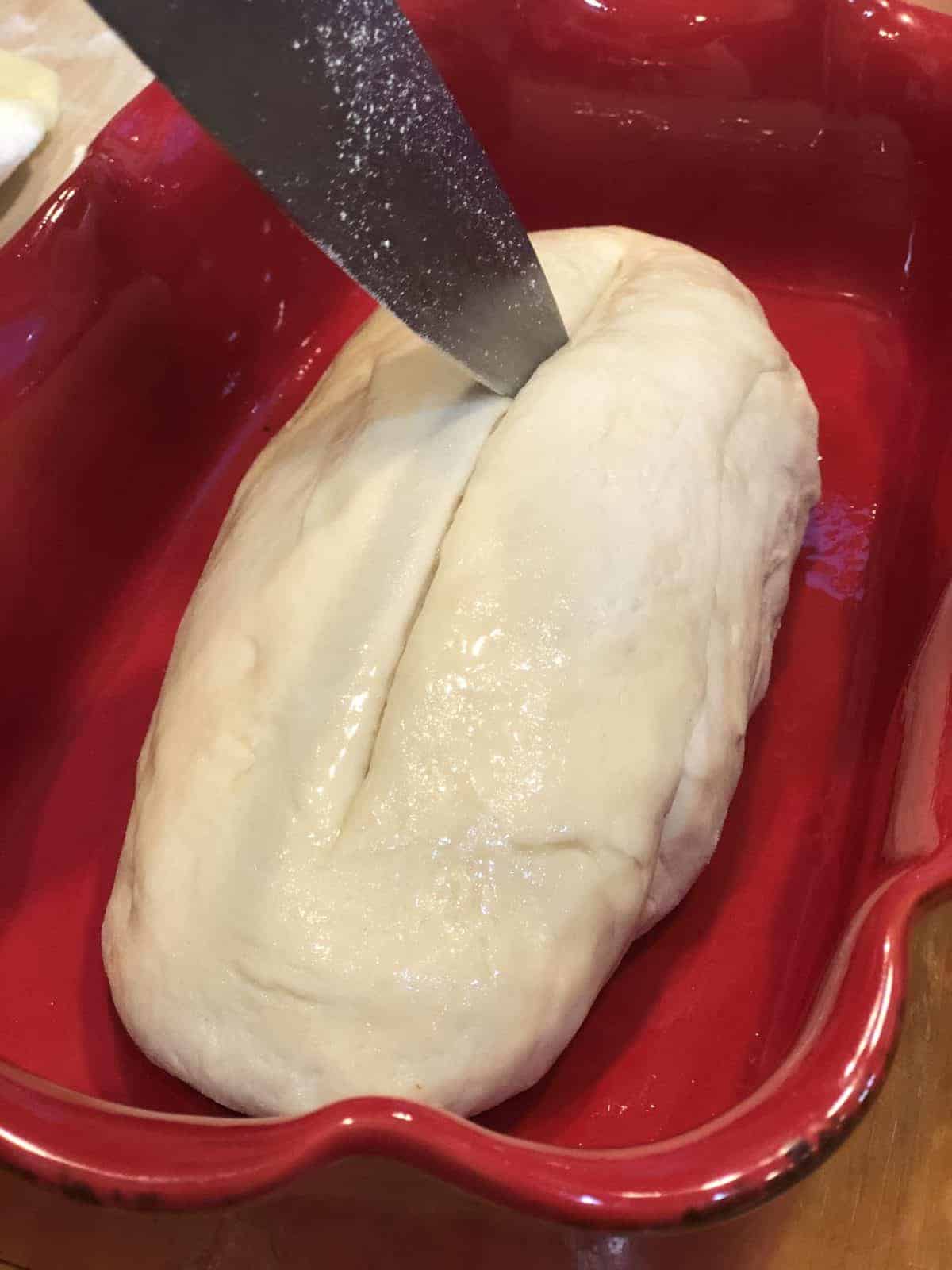 Preparing Homemade Dough for Baking by slicing the dough down the middle with a stainless steel knife