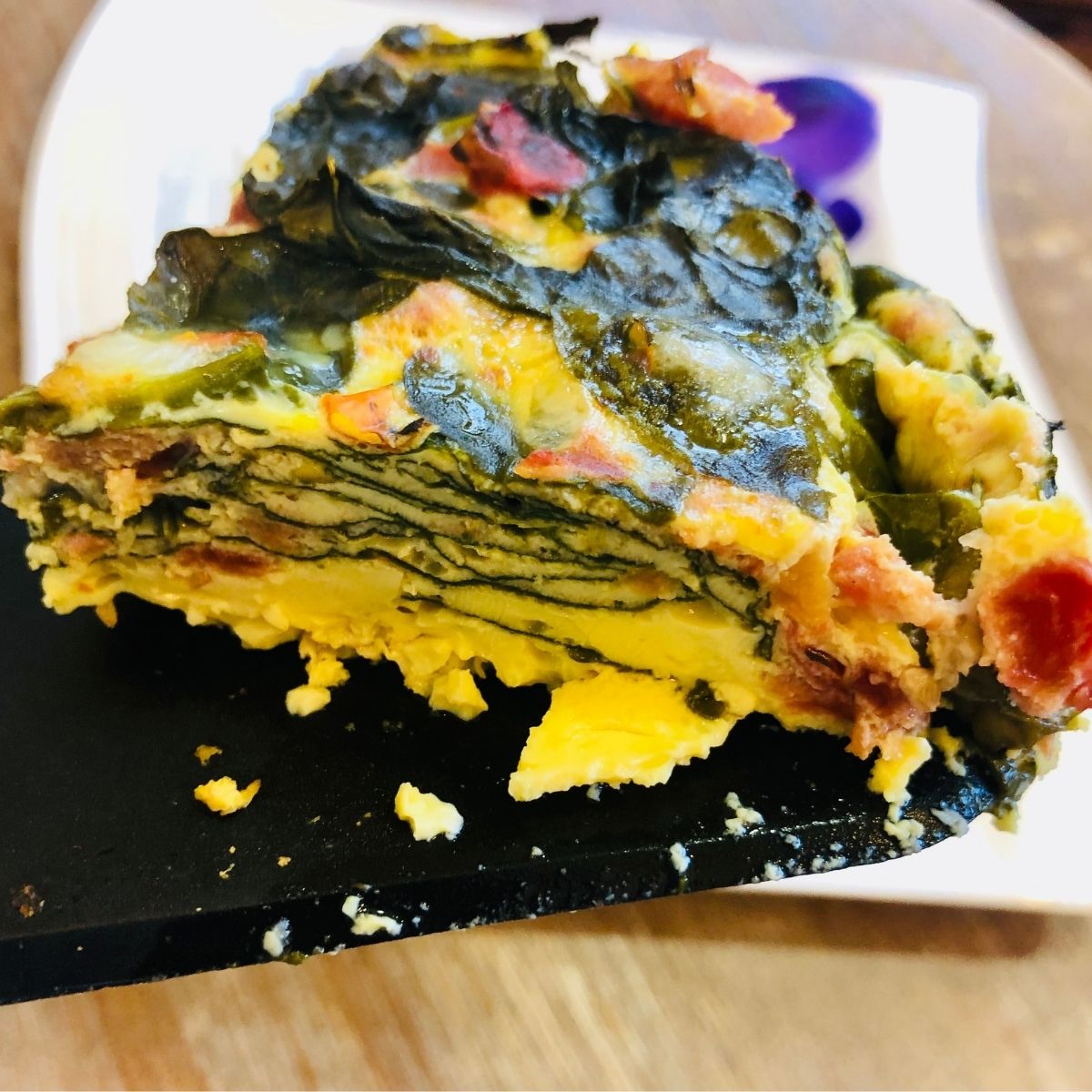 a slice of crockpot spinach parmesan frittata on a black spatula