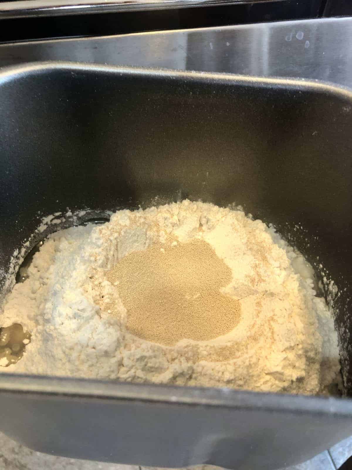 Flour yeast and vegetable oil in the bucket of a bread making machine