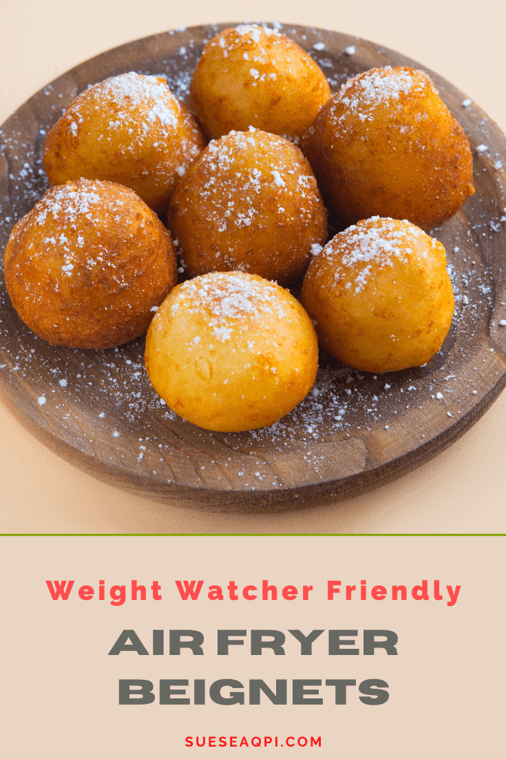 7 Air Fryer Beignets on a wooden platters sprinkled with powdered sugar