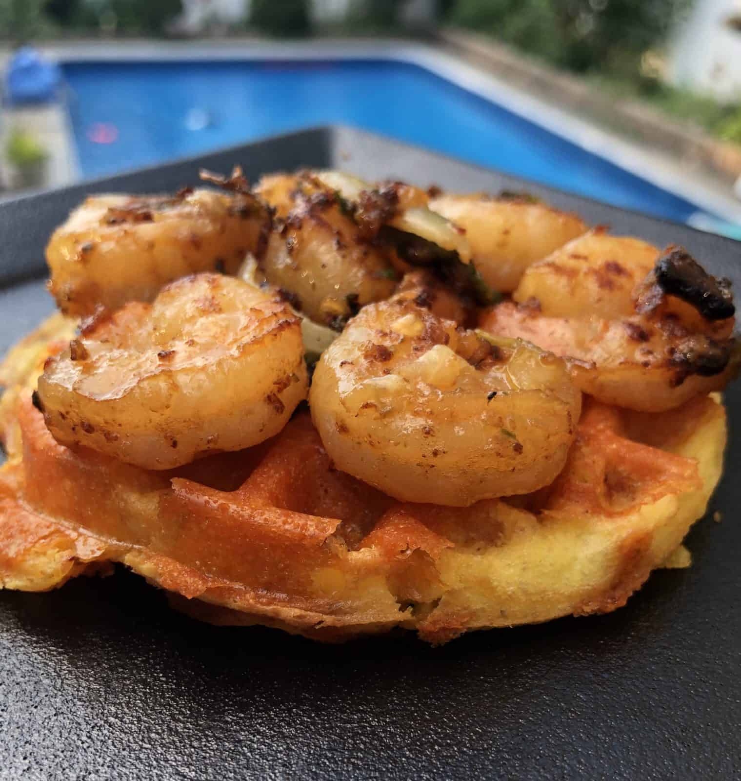 Grilled Shrimp on a Chaffle on a square black plate next to a pool