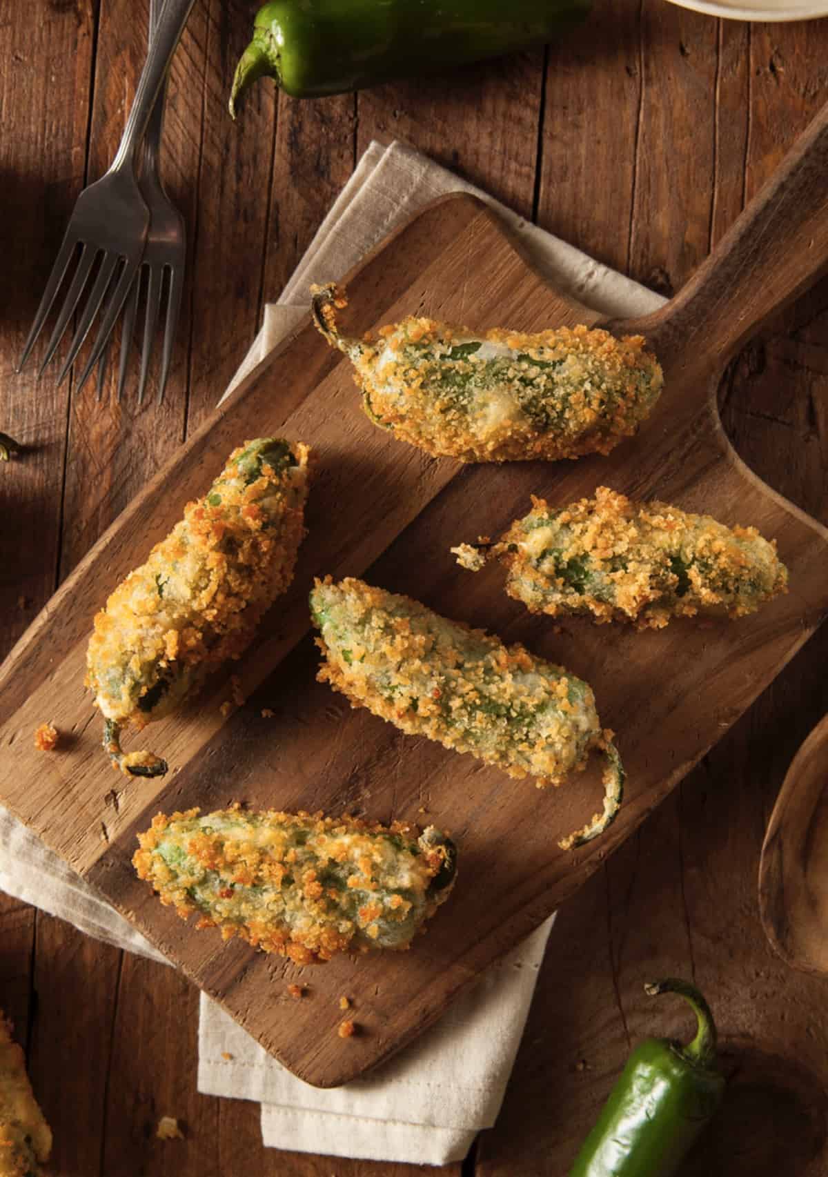 four Fresh Baked Jalapeno Poppers on a wooden cutting board