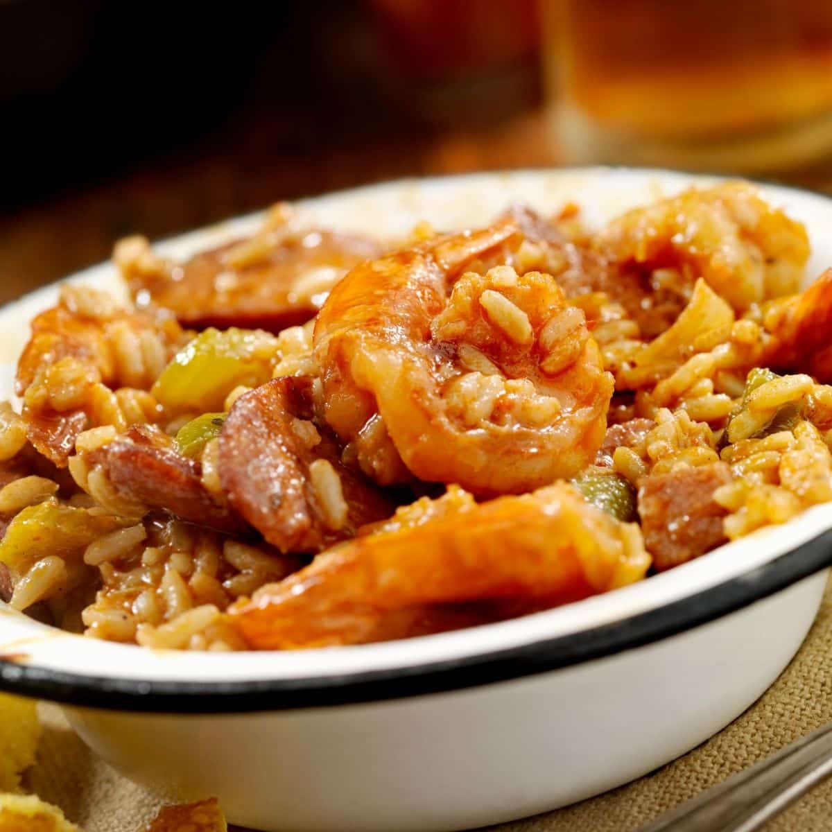Shrimp jambalaya in a white bowl with a blue stripe on a wooden table