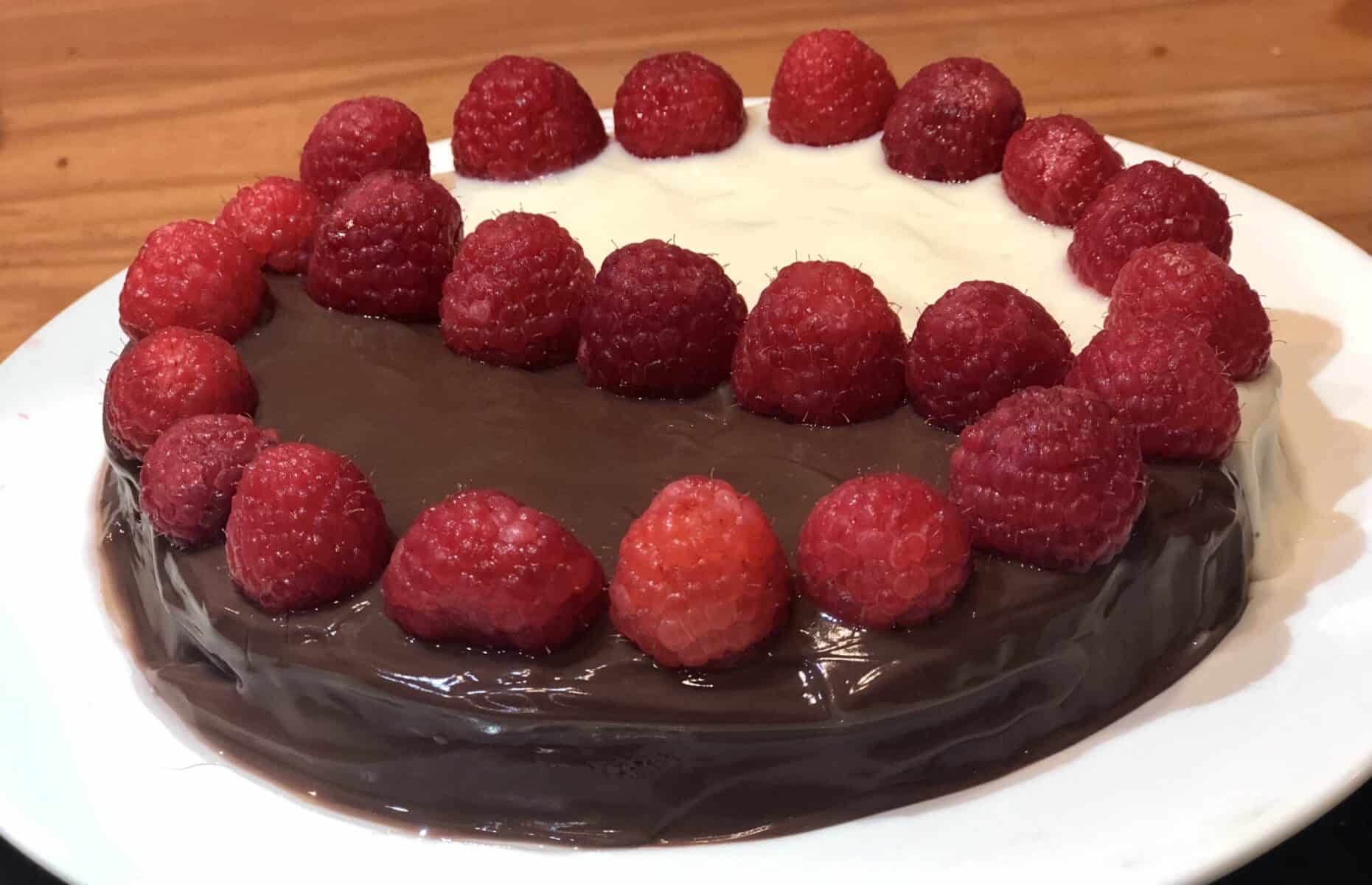 Black and White Air Fryer Cake with Raspberries on top on a white plate
