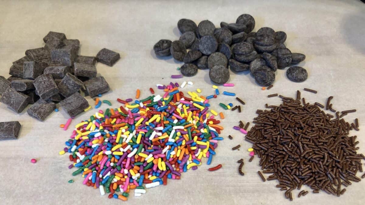 Colored Sprinkles and Chocolate Chips and chocolate chunks and chocolate sprinkles on a sheet of white parchment paper