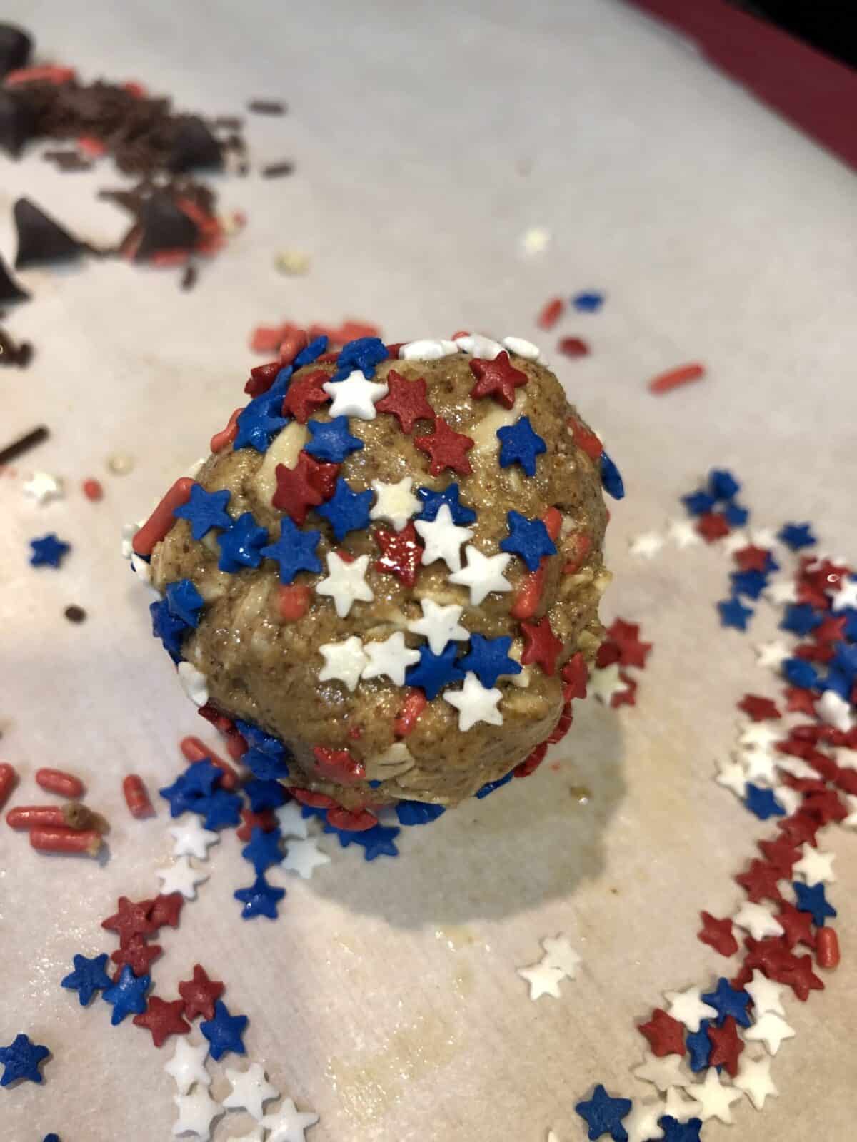 vanilla almond protein bite with red white and blue star sprinkles on a sheet of white parchment paper