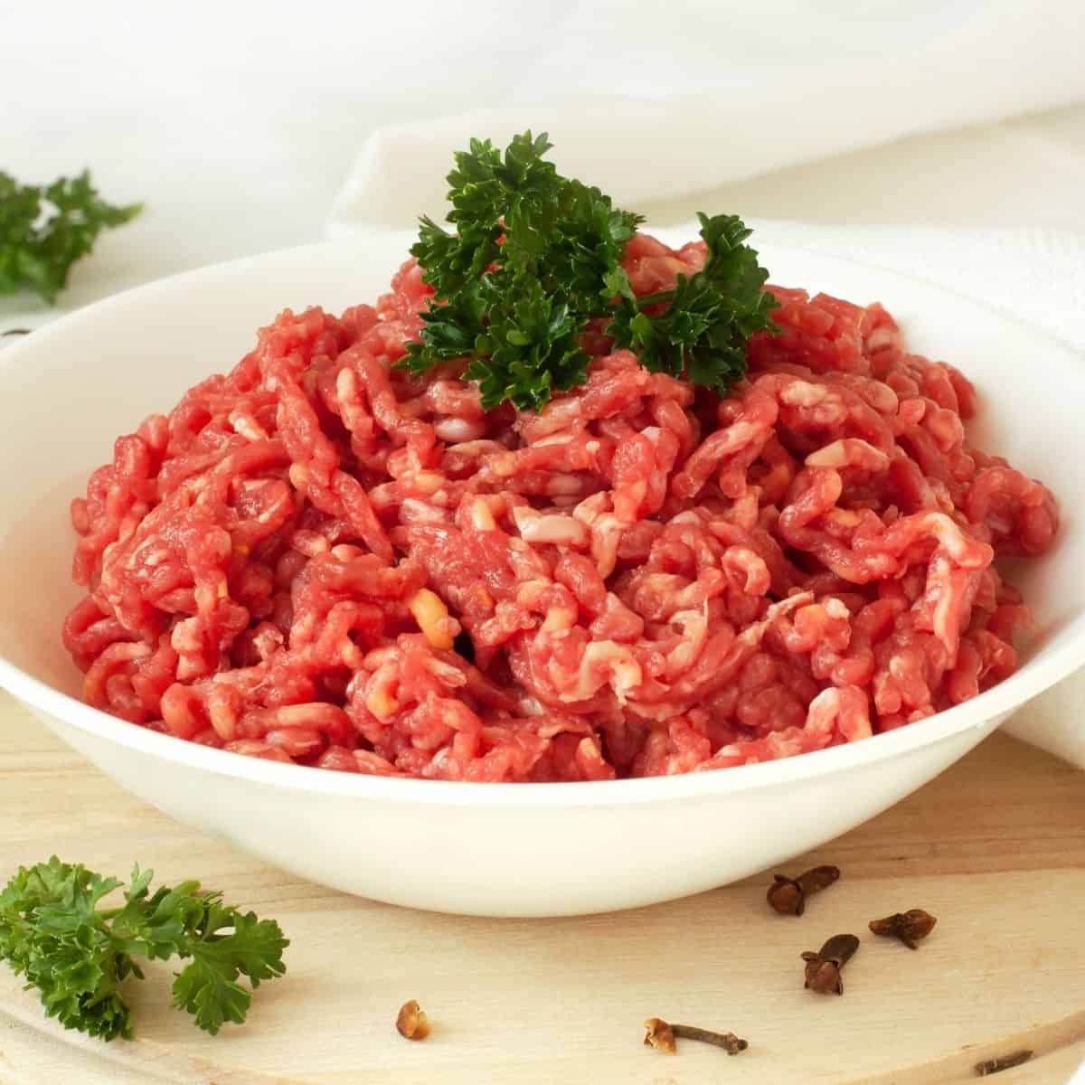 Chop Meat in a white bowl with fresh parsley on top of the meat