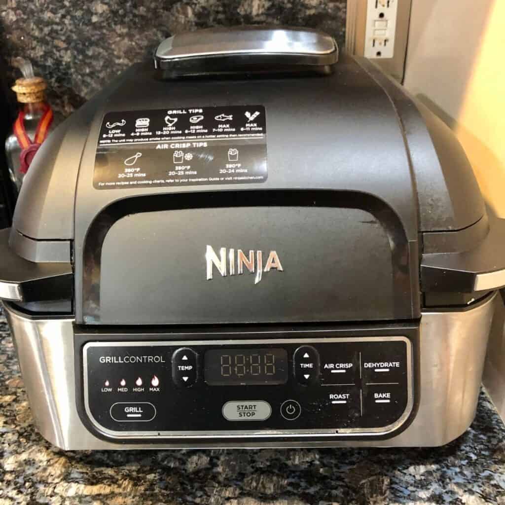 Ninja Foodie Air Fryer sitting on a black granite counter top