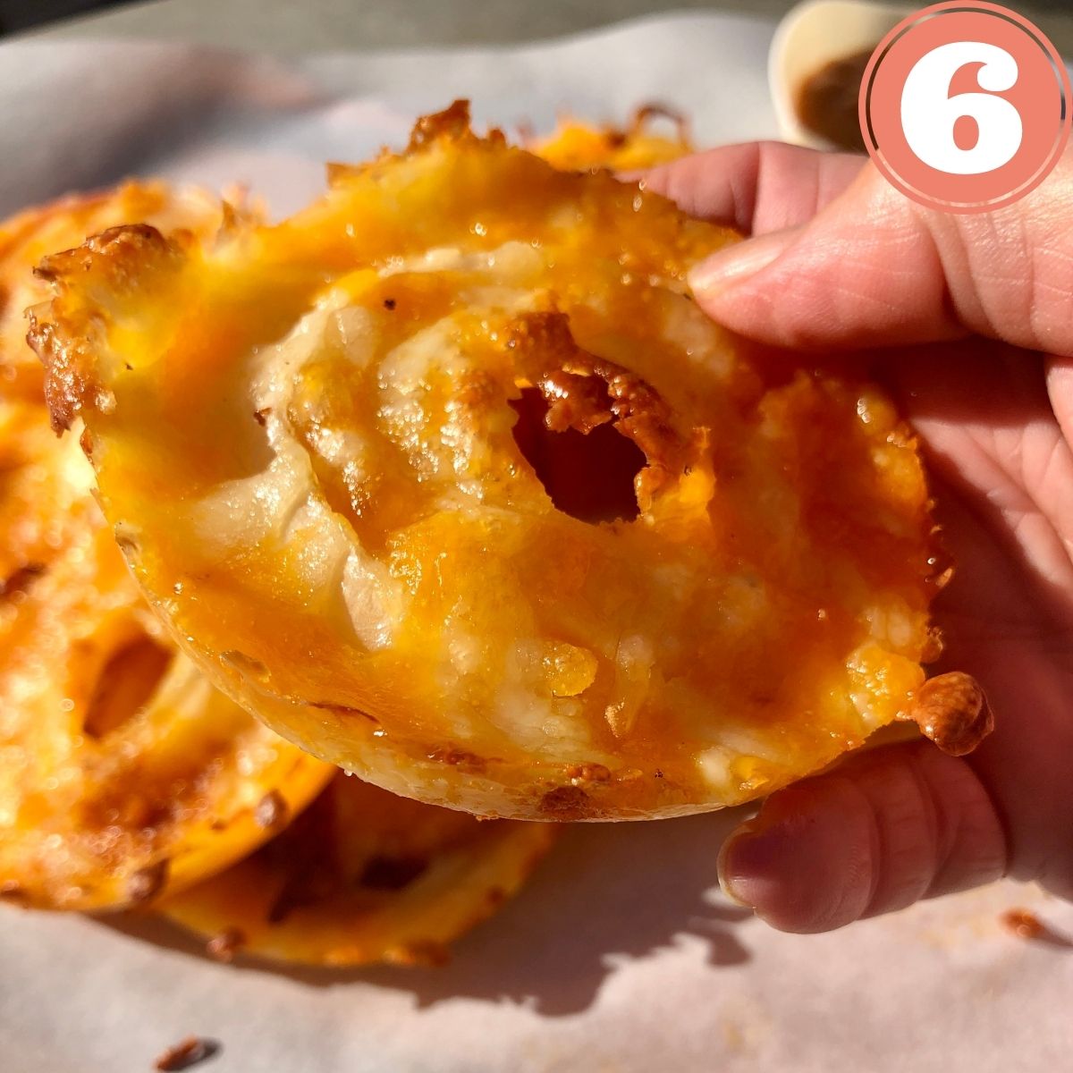 a hand holding a homemade cheddar cheese onion ring