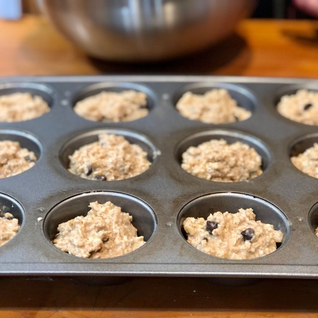 Weight Watcher Oatmeal Banana Chocolate Chip muffin batter in a muffin tin on a wooden table