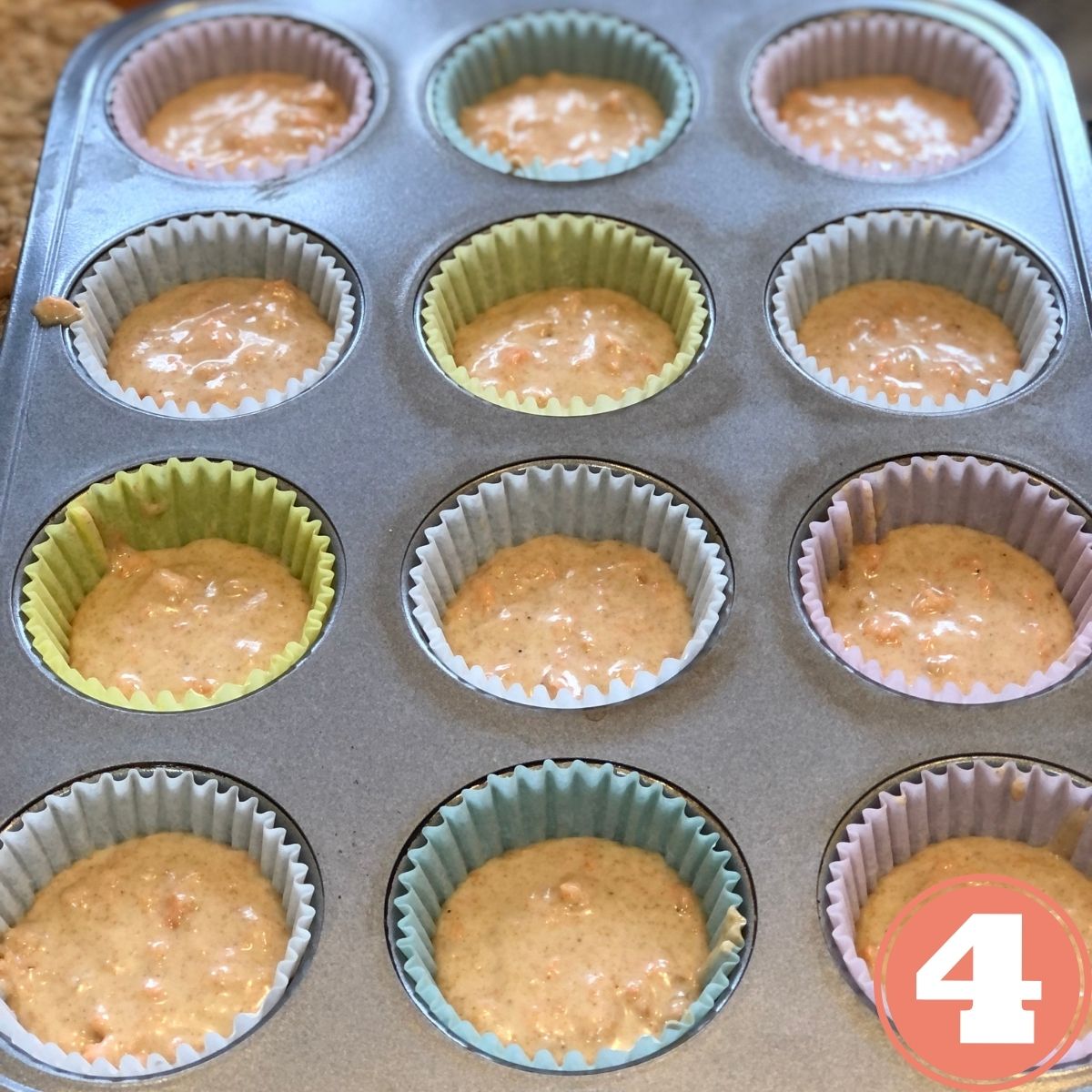 Carrot cake muffin batter in a paper muffin liners in a muffin baking pan