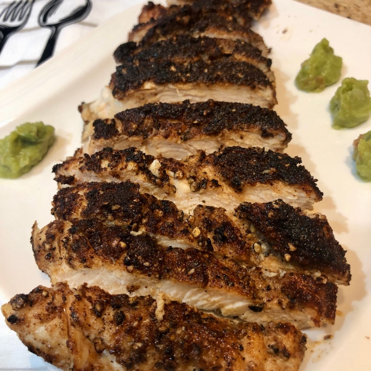 Sliced cast iron chicken strips on a white plate with avocado