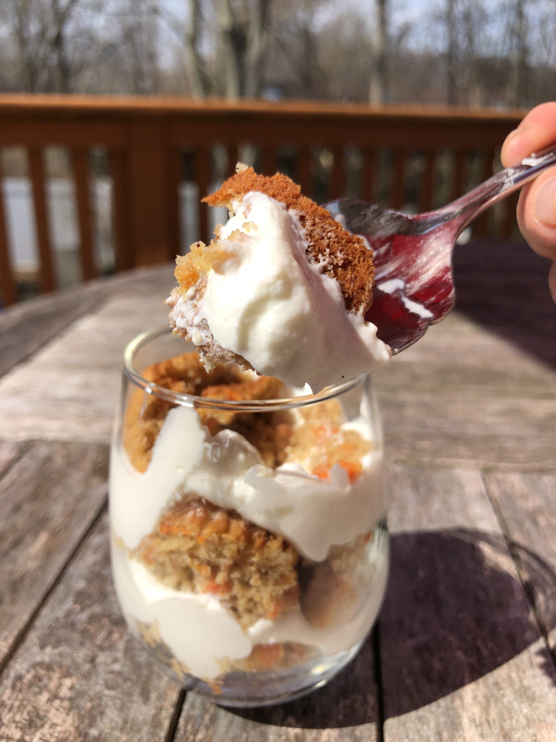 carrot cake muffin parfait with whipped cream in a clear glass with a spoon