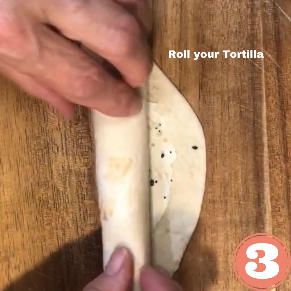 Hands rolling a tortilla on a wooden cutting board