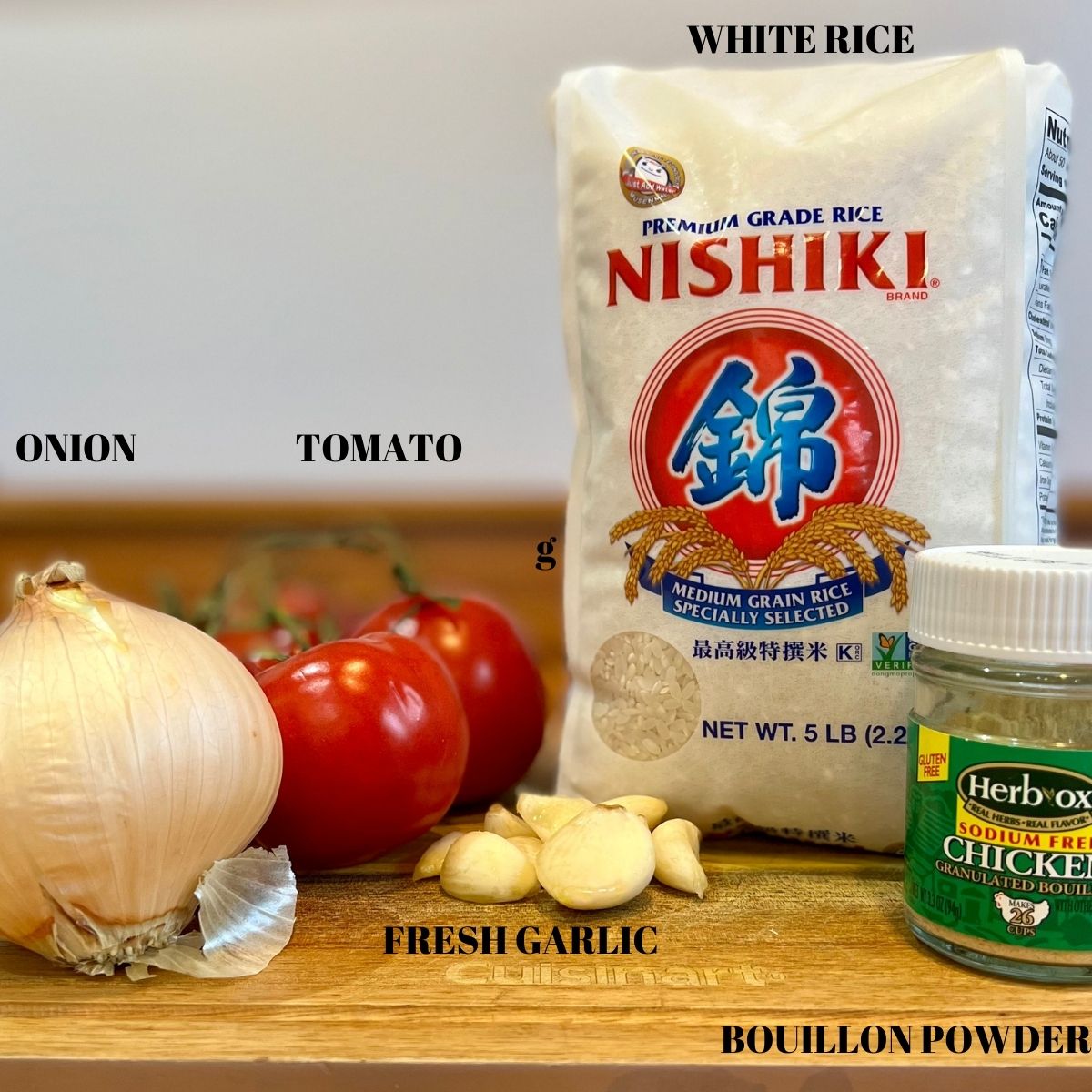 Ingredients for Arroz Rojas - White Rice, Onion,Tomatoes,garlic and bouillon powder on a wooden cutting board