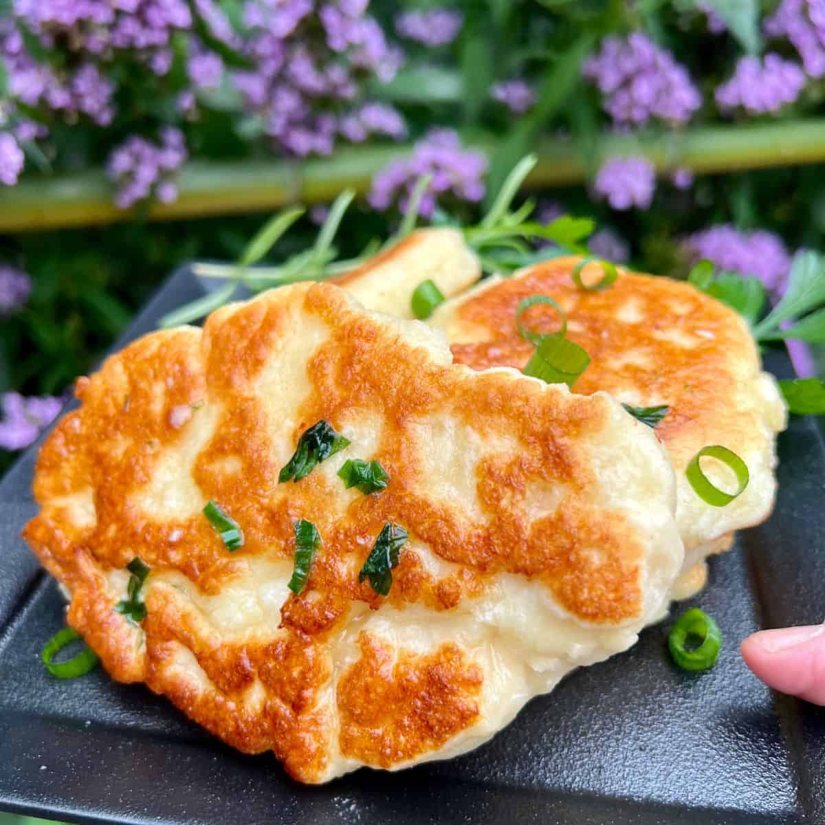 Gluten Free Naan Bread slices on a black plate with chives