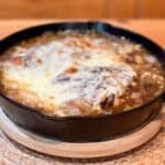 French Onion Chicken Bake in a black cast iron skillet on a wooden lazy Susan