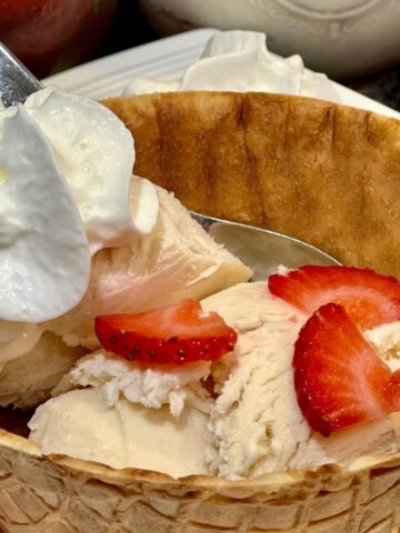 Mason jar strawberry ice cream in a wafer bowl with sliced strawberries and whipped cream