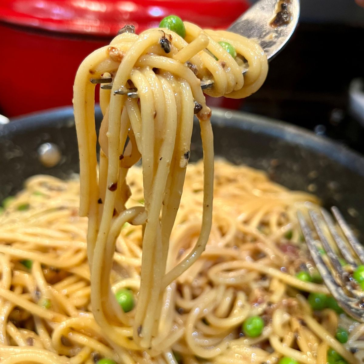 Weight Watchers Spaghetti carbonara with peas on a ford over a pan of pasta