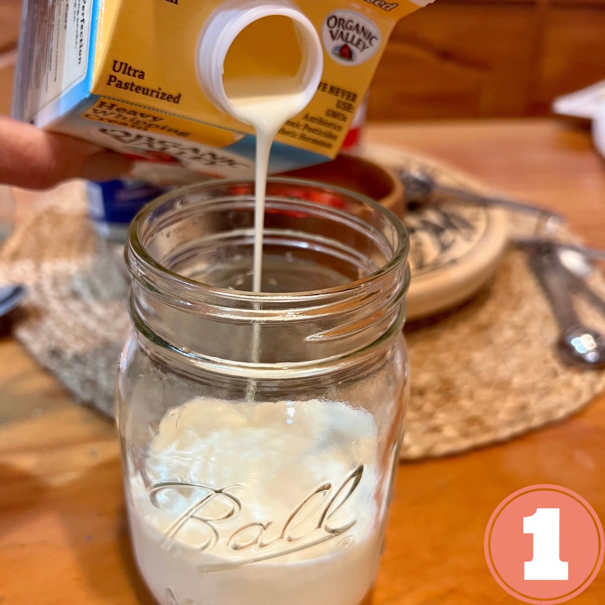 Heavy whipping cream being poured into a glass mason jar