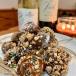 Two ingredient chocolate truffles stacked on a plate with 2 wine bottles and a candle